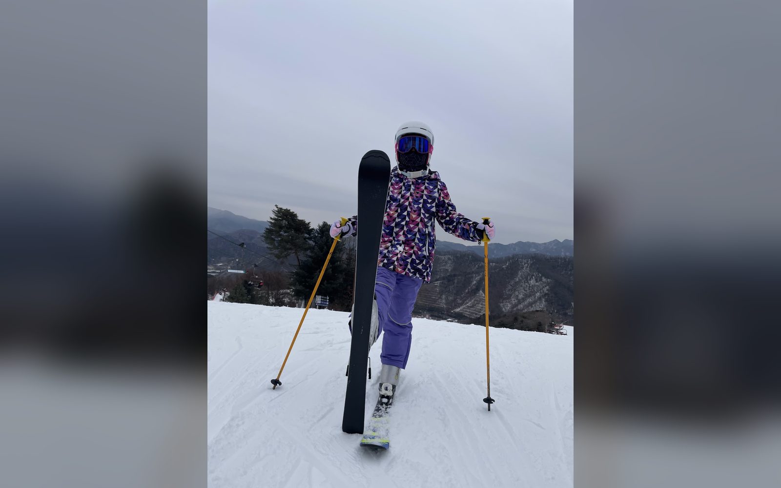 스키를 세워 들고 산을 바라보는 아이