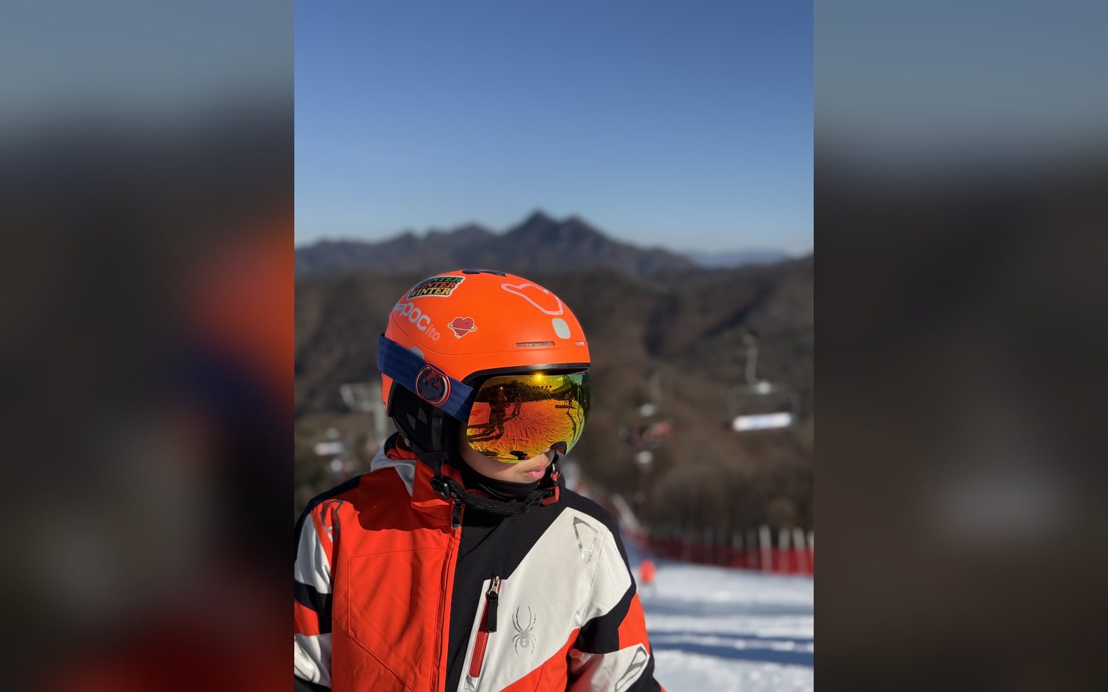 주황 헬멧과 고글을 쓰고 리프트 앞에 선 아이