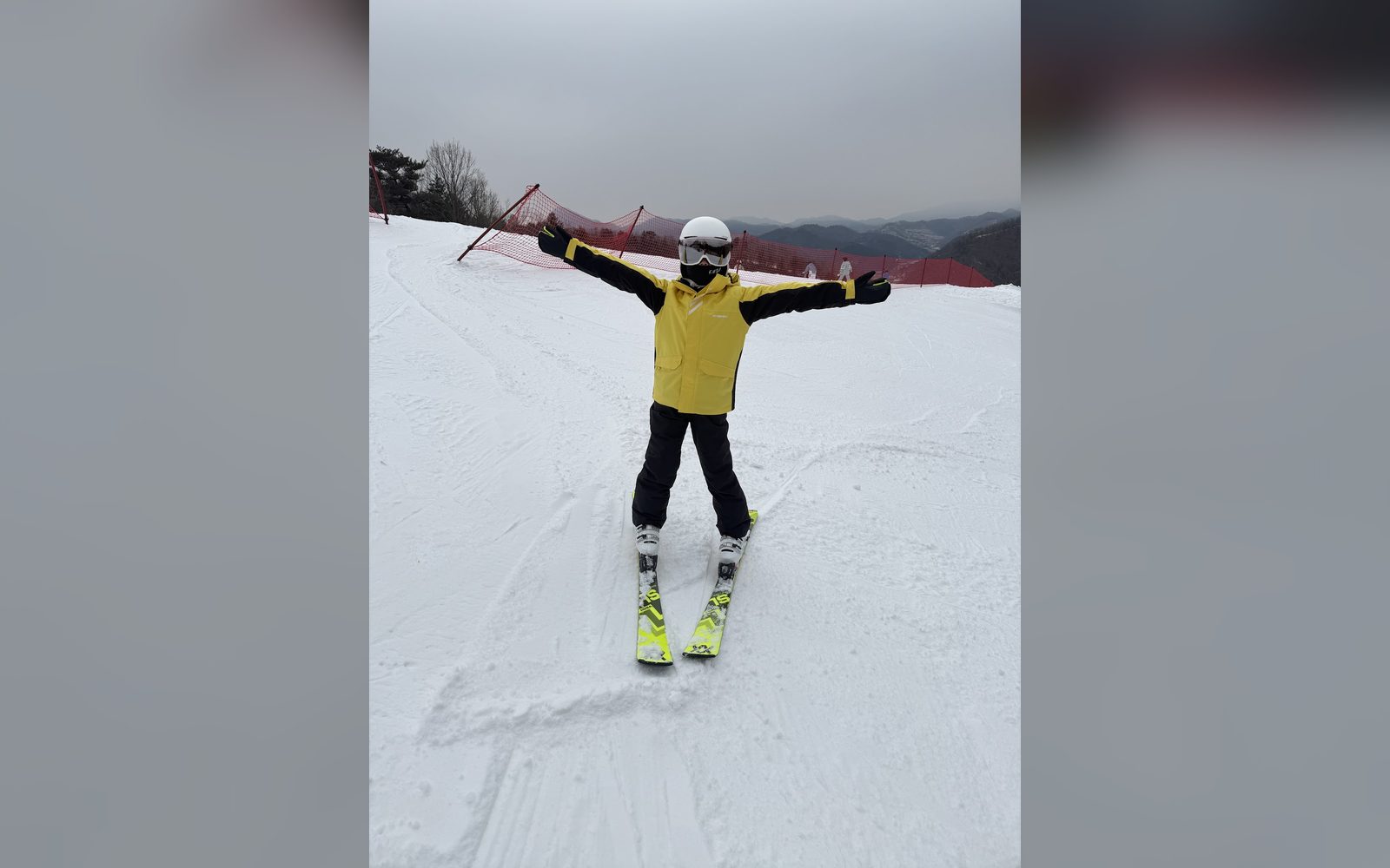 노란 재킷을 입고 두 팔을 벌려 균형을 잡는 아이