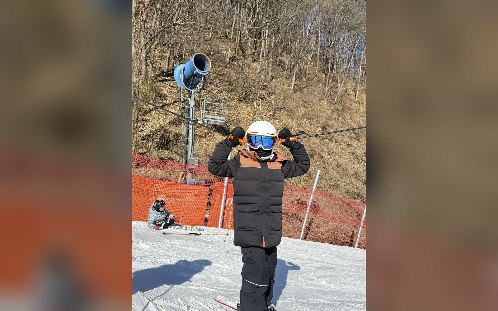 제설기 옆 슬로프에서 헬멧을 고쳐 쓰는 아이