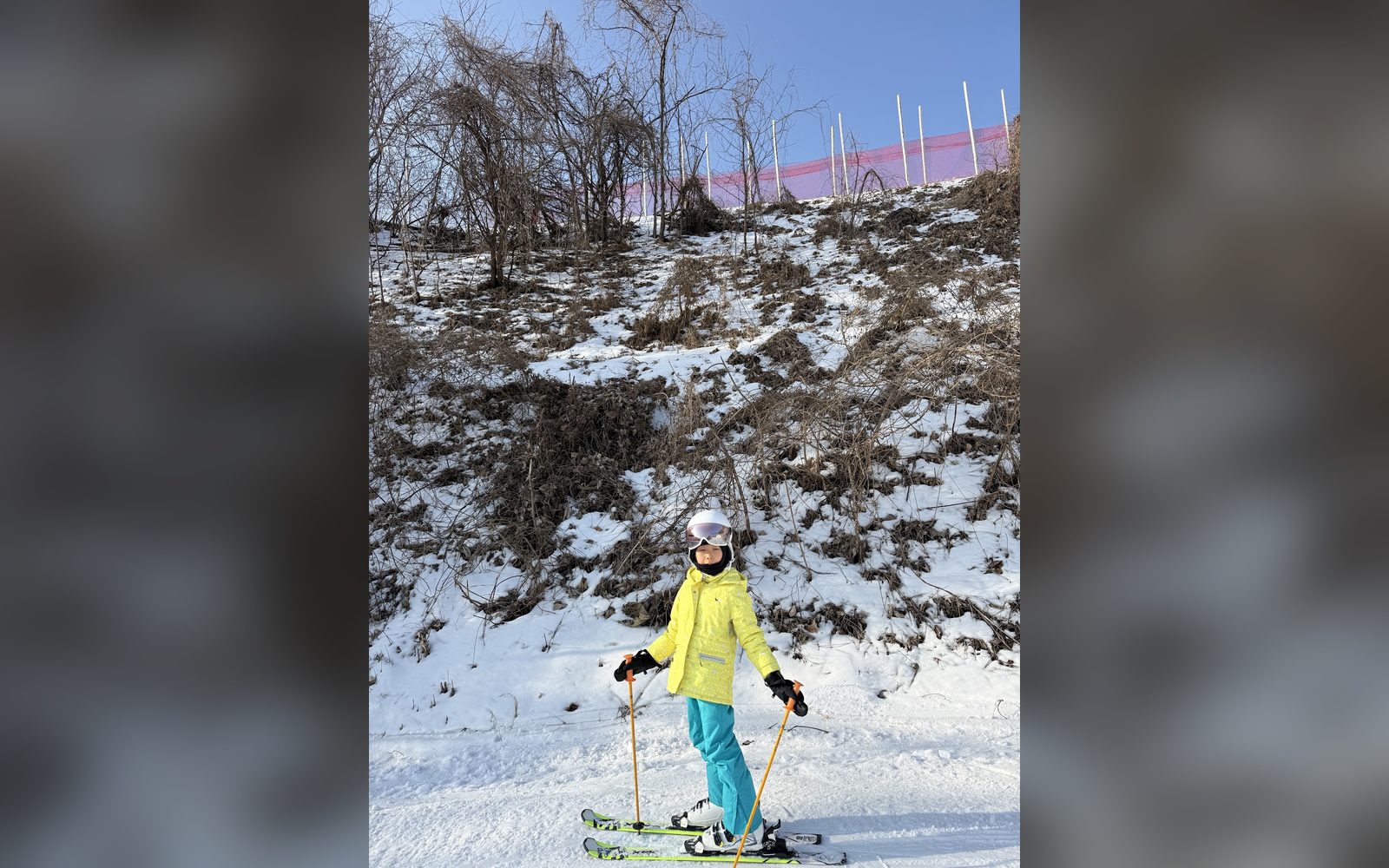 노란 재킷을 입고 눈 덮인 언덕 앞에 선 아이