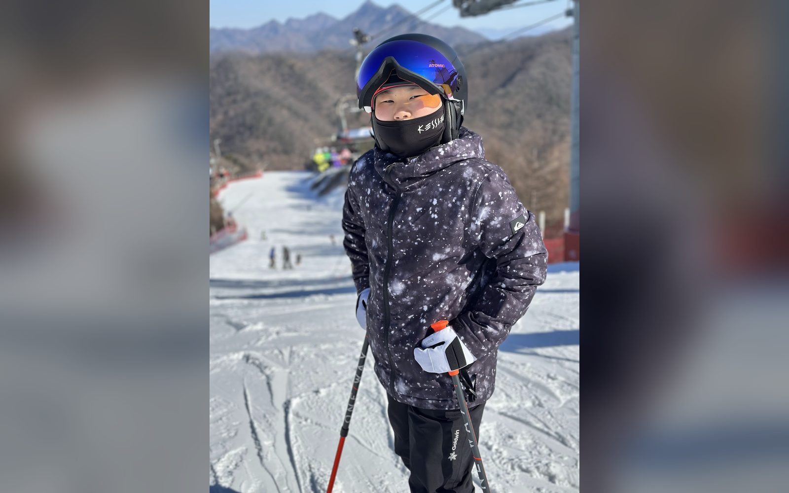 별무늬 재킷을 입고 슬로프 위에 선 아이