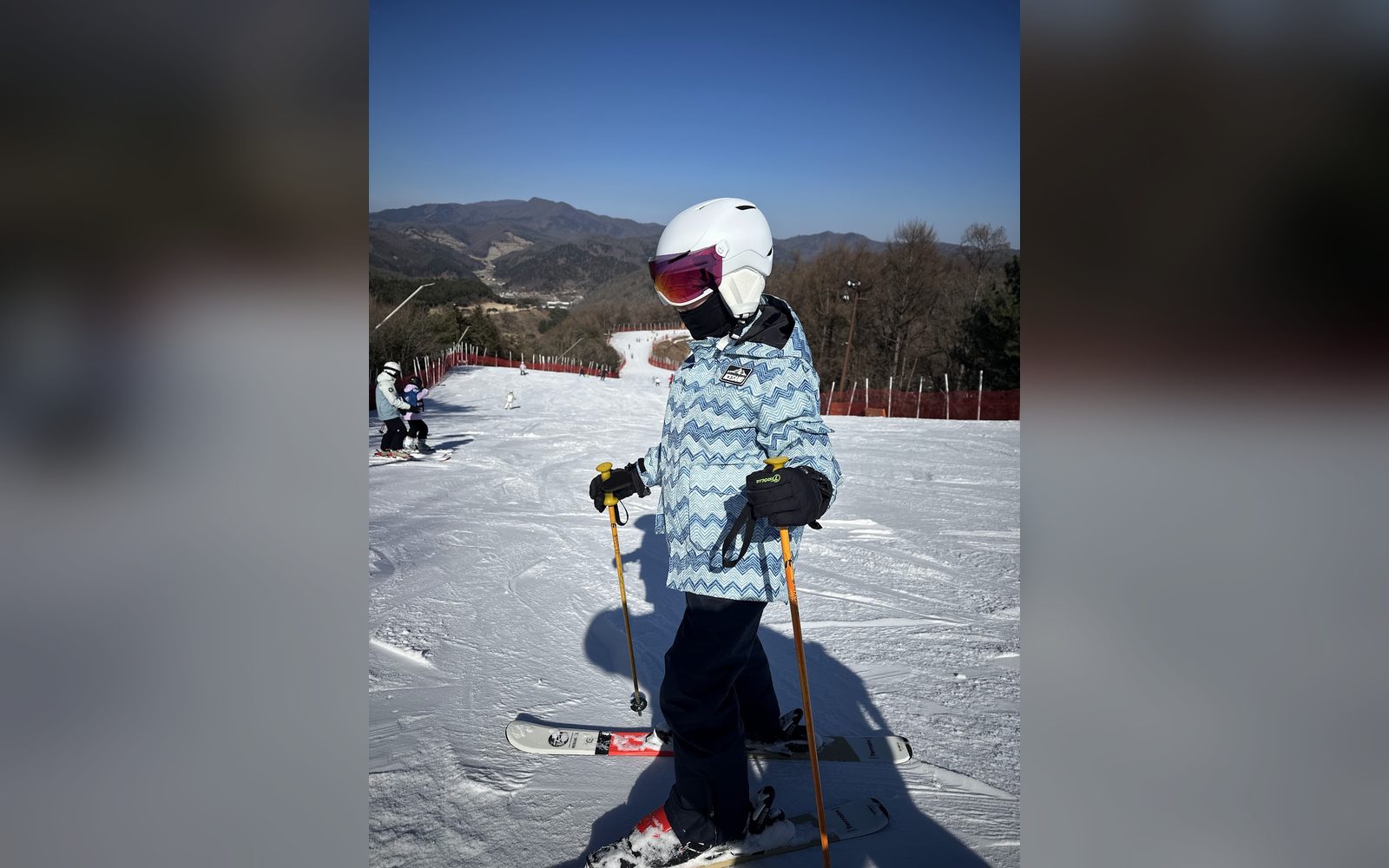 하늘색 재킷을 입고 슬로프에 선 아이