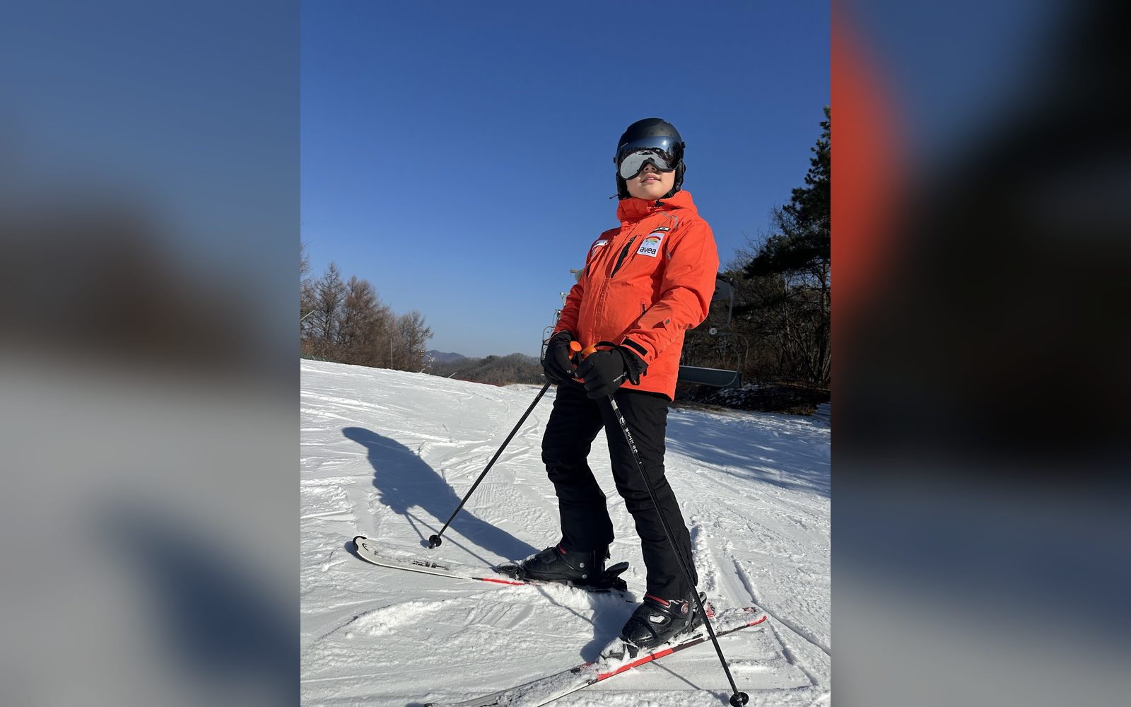 주황 재킷을 입고 슬로프에 선 아이