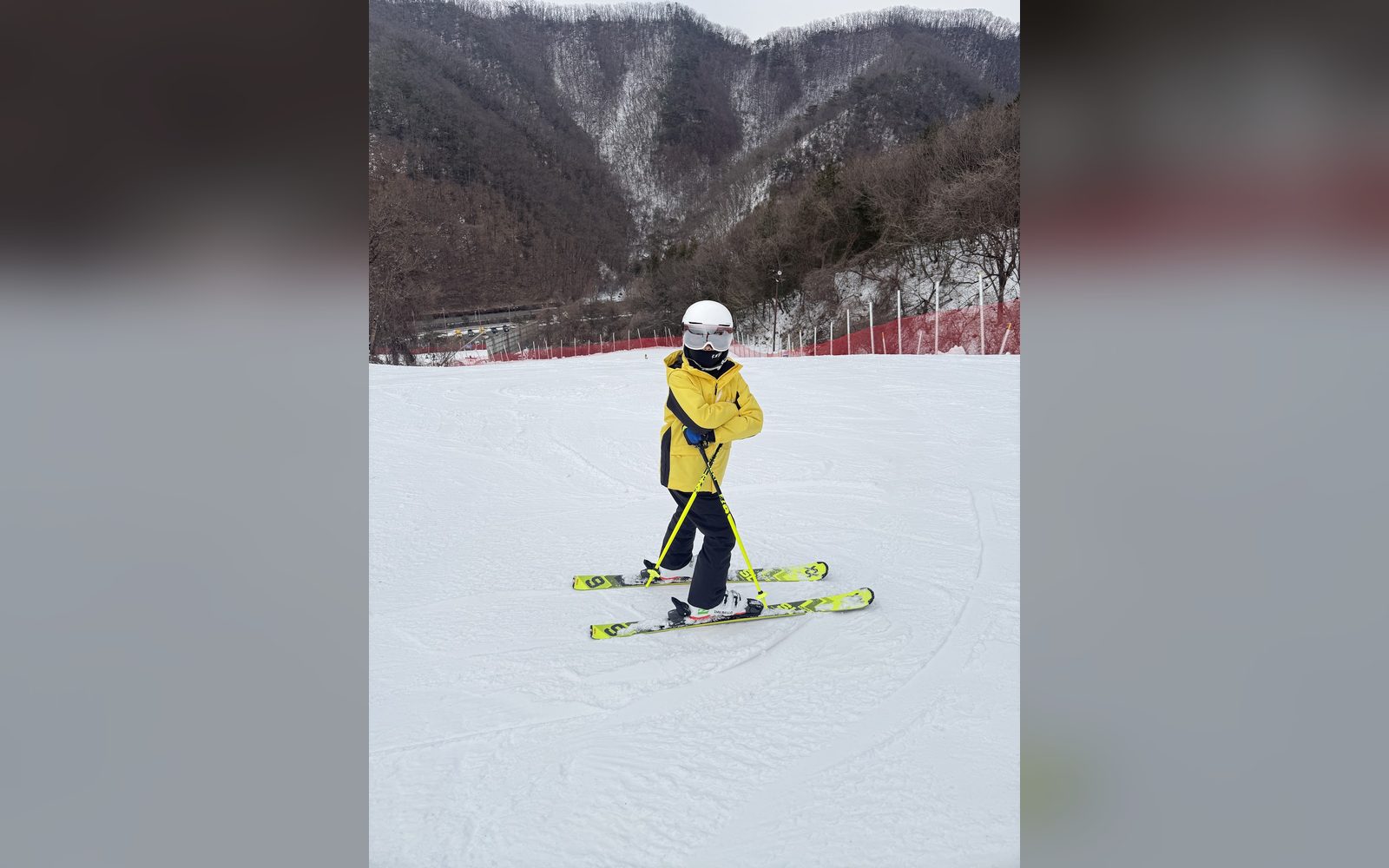 넓은 슬로프에 선 노란 재킷의 아이