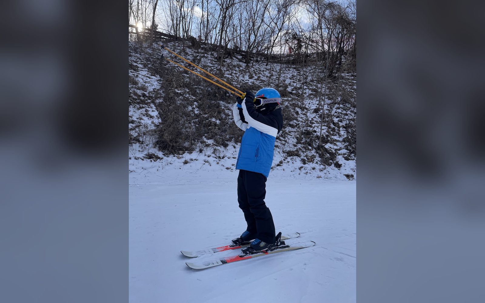 폴을 어깨에 메고 슬로프에 선 아이