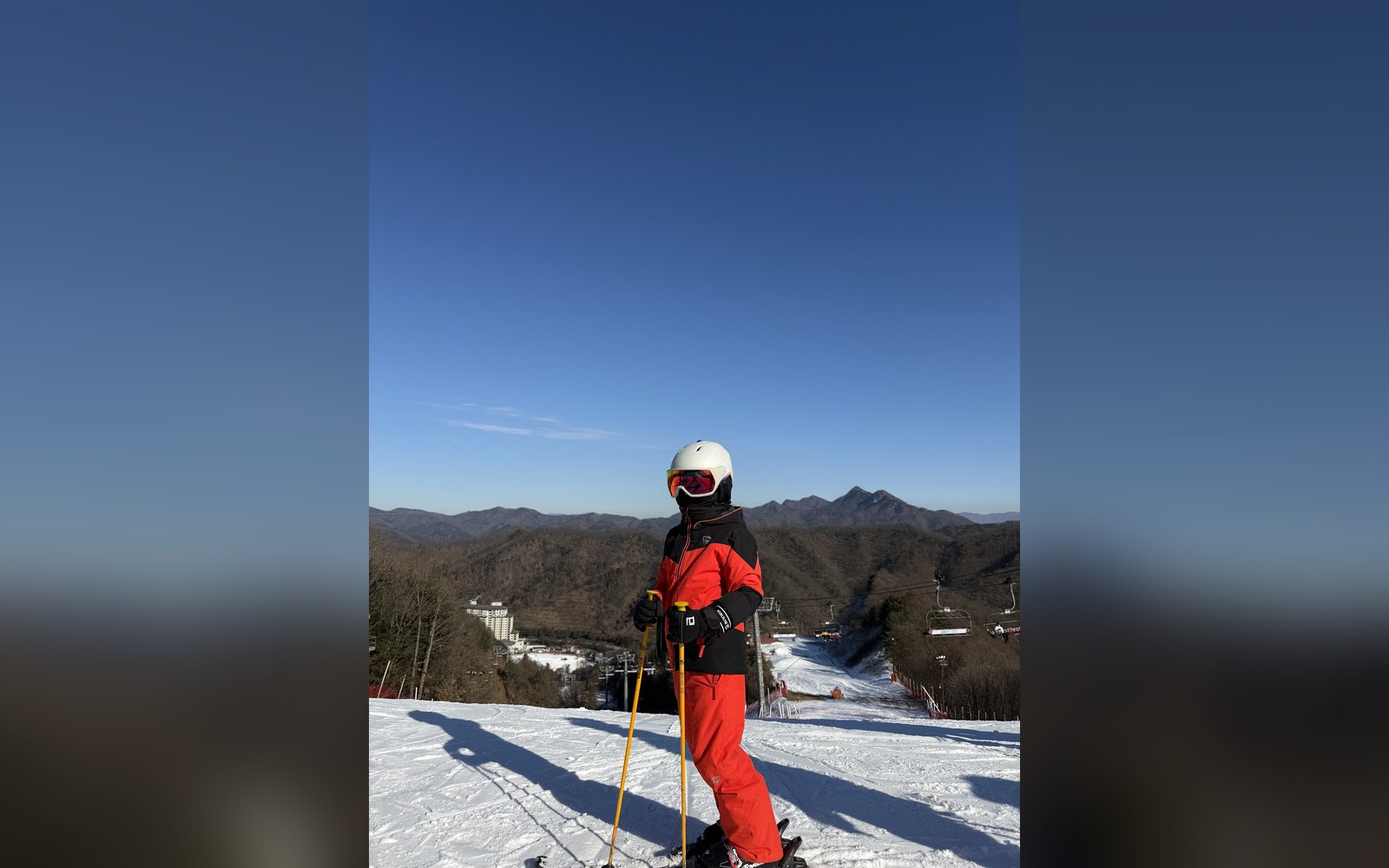 산을 등지고 선 빨간 스키복 아이